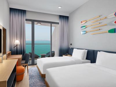 Helles Hotelzimmer mit zwei Einzelbetten, Meerblick, moderner Deko und Balkon mit Sitzbereich.