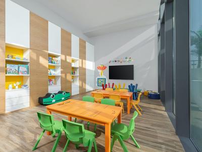 Hell eingerichteter Kinderspielraum mit bunten Stühlen und großen Fenstern.