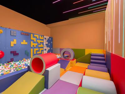 Bunten und gemütlichen Kinderspielbereich mit Kletterwand, Tunnel und weichen Matten in einem Hotel.