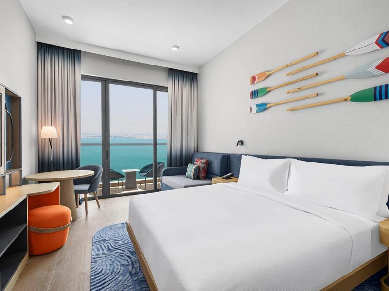 Modernes Hotelzimmer mit großem Bett, Meerblick und maritimer Dekoration mit Paddeln an der Wand.