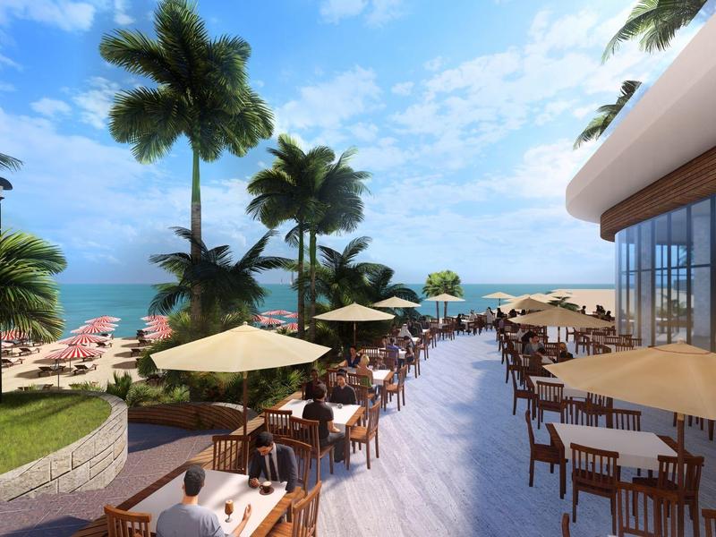 Blick auf eine Terrasse mit Stühlen, Tischen, Sonnenschirmen, Palmen und Meer im Hintergrund.