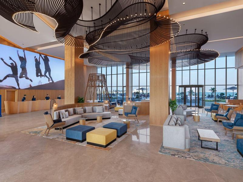 Geräumige Hotellobby mit modernen Sitzbereichen und großem Wandbild.