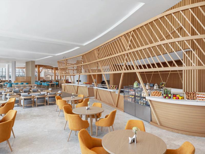 Modernes, helles Restaurant mit gelben Sesseln und einem großen Buffetbereich.