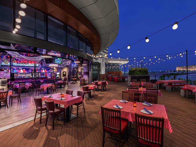 Gemütliche Außenterrasse mit rot gedeckten Tischen und stimmungsvoller Beleuchtung am Abend.