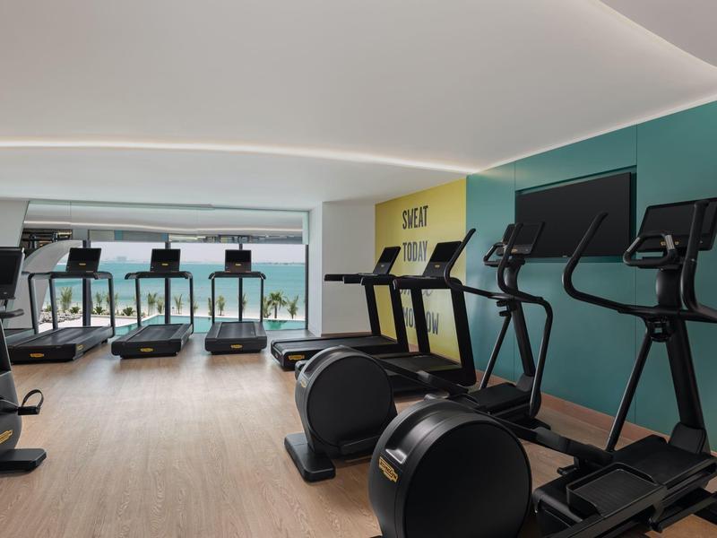 Moderner Fitnessraum mit mehreren Cardiogeräten und Meerblick durch große Fenster