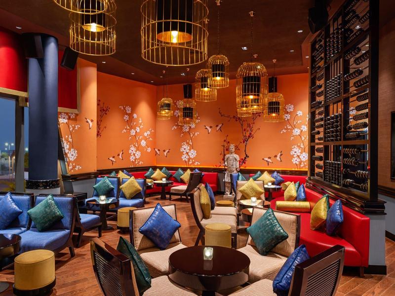 Gemütliche Hotellounge mit bunten Kissen und goldfarbenen Lampen an der Decke.