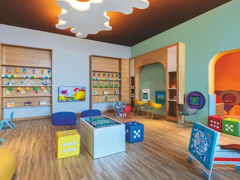 Bunter Kinderspielraum mit Sitzwürfeln, Regalen und Spielzeug in modernem Design.