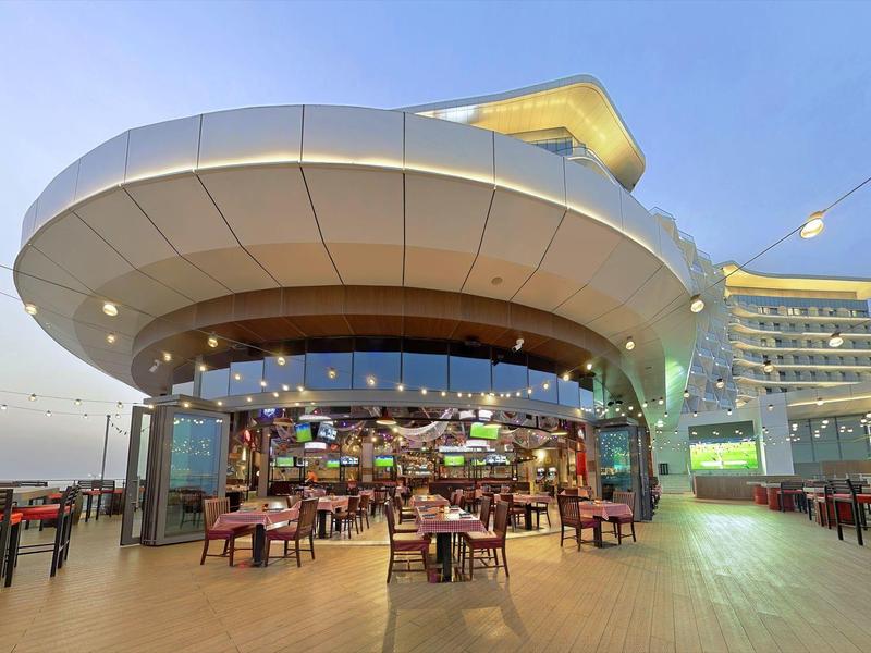 Außenbereich eines modernen Restaurants mit Tischen und Stühlen unter einer futuristischen hellen Dachkonstruktion