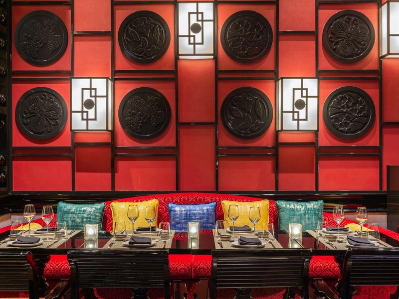 Elegantes Restaurant mit roter Wanddekoration und stilvoll eingedeckten Tischen.