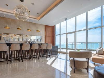Moderner Hotelbarbereich mit hohen Stühlen und Panoramafenstern mit Meerblick.