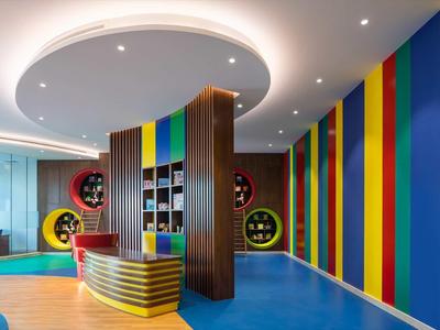 Bunte Hotellobby mit gestreiften Wänden, moderner Rezeption und Sitzbereich.