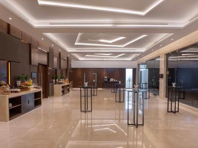 Großer, moderner Hotellobby-Bereich mit hellem Marmorfußboden und stilvoller Beleuchtung an der Decke.