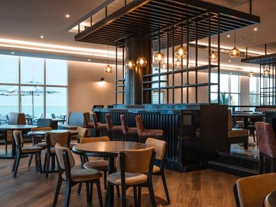 Modern eingerichteter Hotelrestaurantbereich mit Tischen, Stühlen und großen Fenstern.