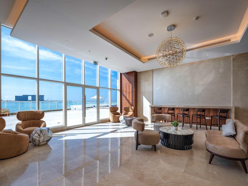 Großer, moderner Wohnraum mit bodentiefen Fenstern, bequemen Sesseln und stilvoller Deckenbeleuchtung.