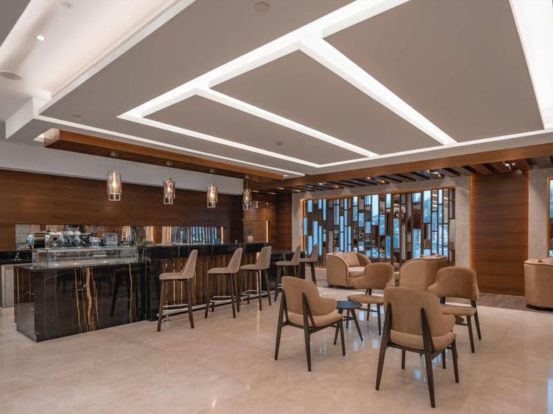 Moderner Aufenthaltsraum mit braunen Sesseln, Holzvertäfelung und hellem Marmorboden.