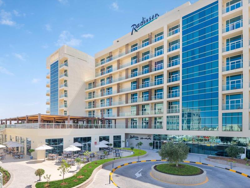 Modernes Hotelgebäude mit großer Glasfassade und Außenbereich mit Terrasse und Pflanzen.