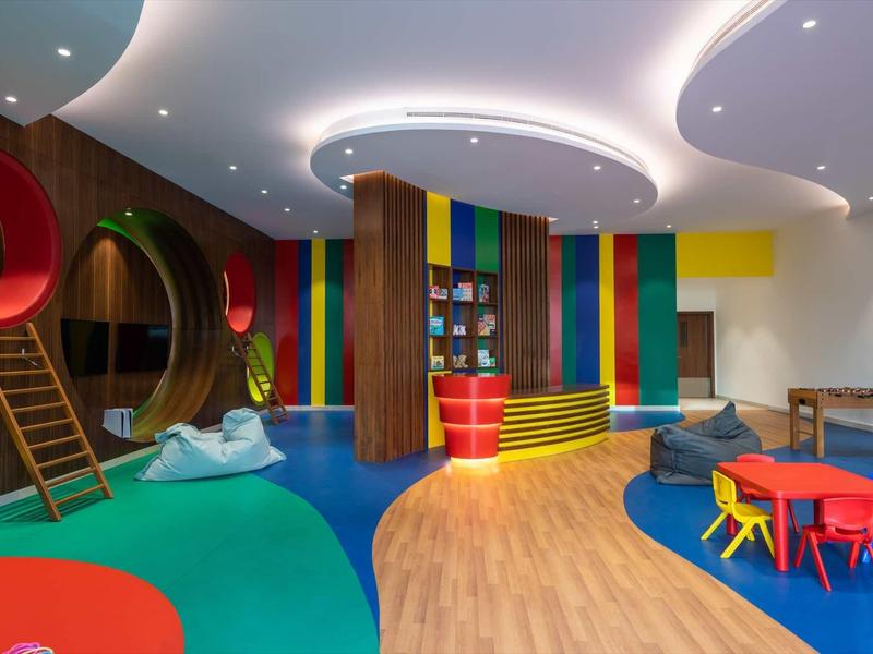 Bunter, moderner Indoor-Spielbereich mit Rutsche, Sitzgelegenheiten und weichem Bodenbelag.