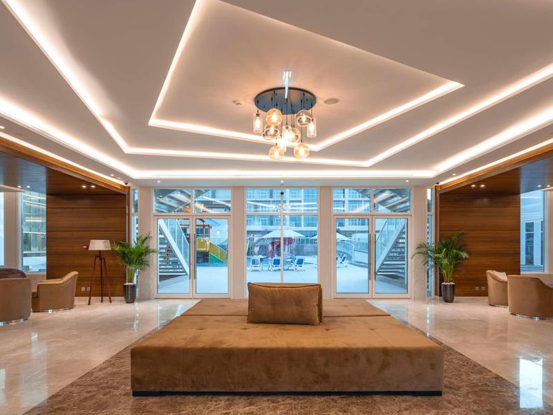 Helles, modernes Lobby mit großen Fenstern, braunen Sitzmöbeln und einer Kronleuchter-Decke.