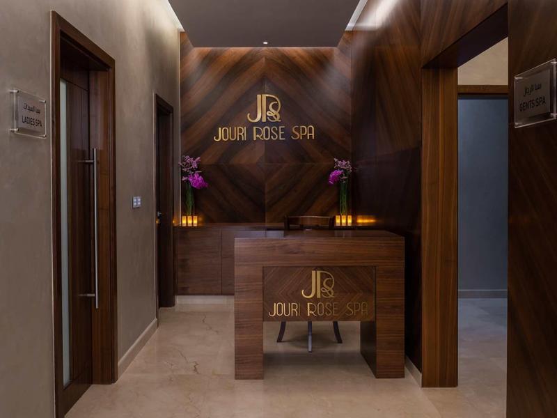 Moderner Spa-Empfang mit Holzakzenten, dunklem Marmor, Orchideen und warmem Licht.