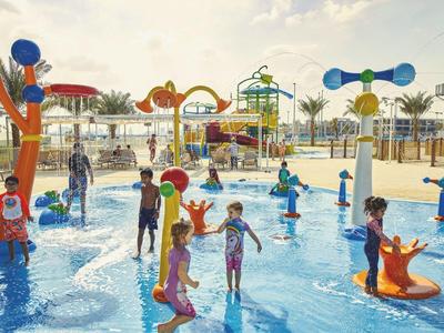 Kinder spielen fröhlich in einem farbenfrohen Wasserspielplatz mit verschiedenen Wasserspielen.