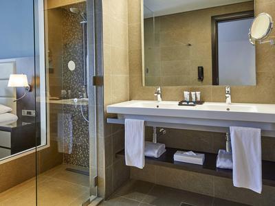 Moderne Badezimmer mit Glasdusche, weißem Waschbecken, Handtüchern und großem Spiegel.