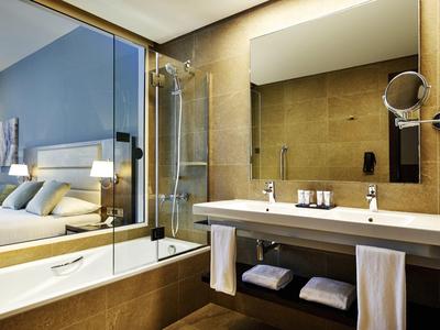Modernes Badezimmer mit großer Badewanne, Glasdusche, Spiegel und Waschbecken mit Handtüchern.