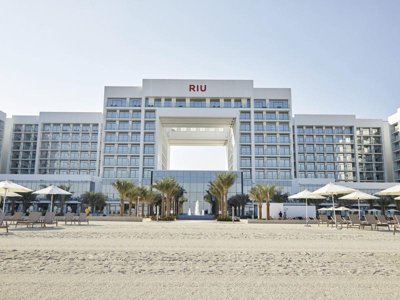 Modern hotel building with large public area and sandy beach in foreground