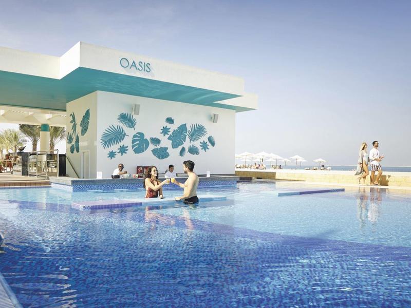 Modern outdoor pool with relaxing guests and pool bar in sunny hotel setting