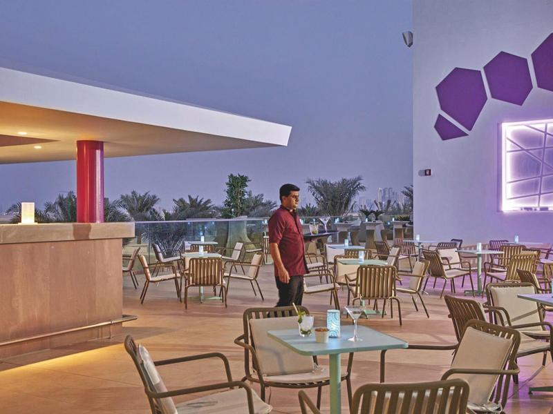 Modern outdoor hotel area with tables, chairs, and decorative lighting at dusk.
