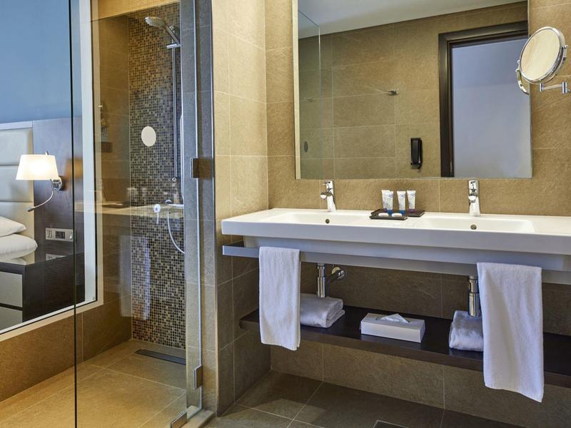 Modern bathroom with sink, mirror, shower, and towels in a hotel room.