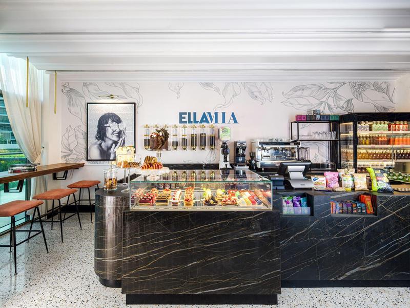 Moderner Café-Innenraum mit schwarzer Marmortheke, Sitzbänken und hellen Marmorwänden.