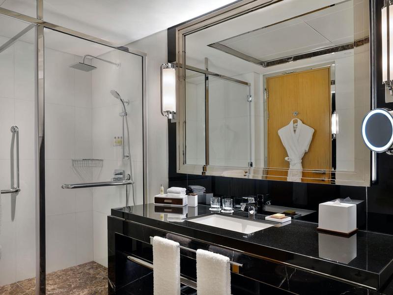 Modernes Badezimmer mit schwarzer Arbeitsplatte, großem Spiegel und Glastür zur Dusche.