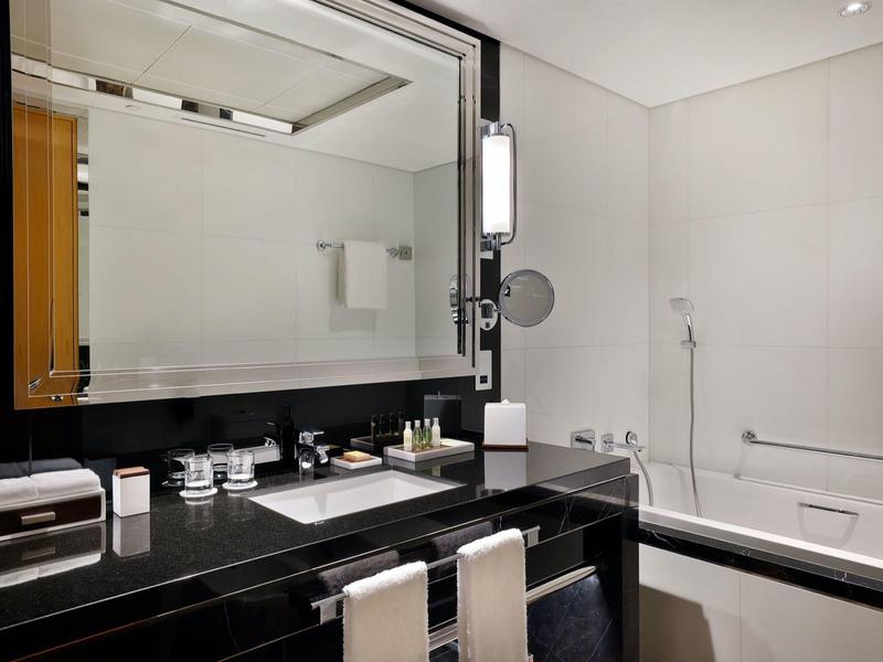 Modernes Hotelbadezimmer mit großem Spiegel, schwarzer Arbeitsplatte und Badewanne.