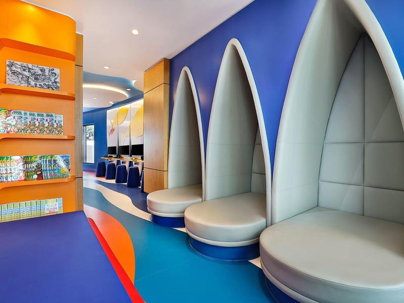Modernes Hotel mit hellen, organisch geformten Sitznischen und buntem Bodenbelag.