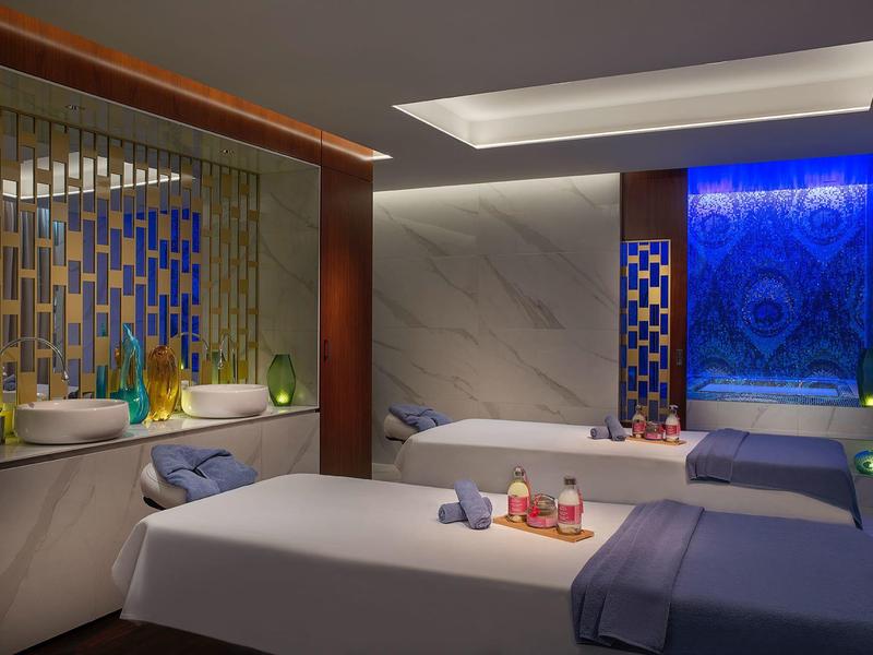 Ruhiger Spa-Raum mit zwei Massageliegen, dekorativem Licht und entspannenden Accessoires.