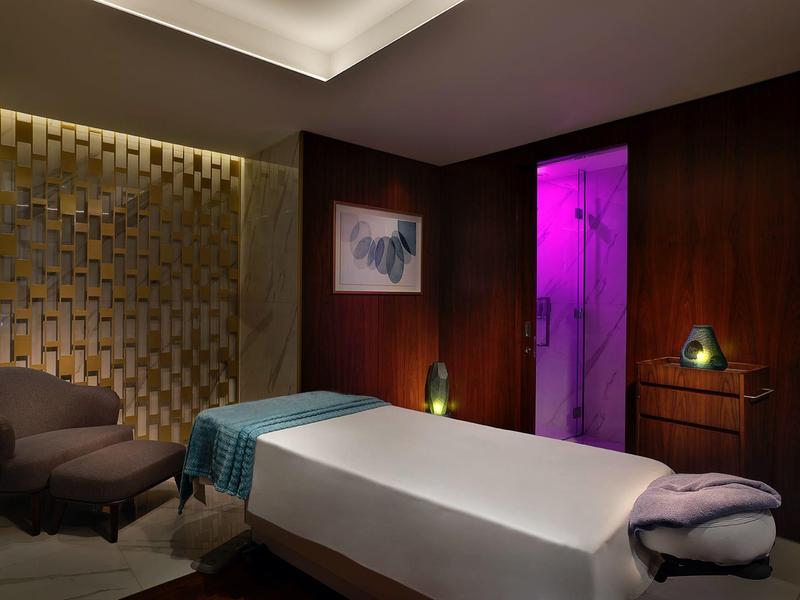 Gemütlicher Spa-Raum mit Massageliege, bequemen Stuhl und stimmungsvoller Beleuchtung.