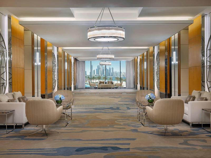 Großer, luxuriöser Hotellobby mit bequemen Sesseln, Teppichboden und Kronleuchtern.