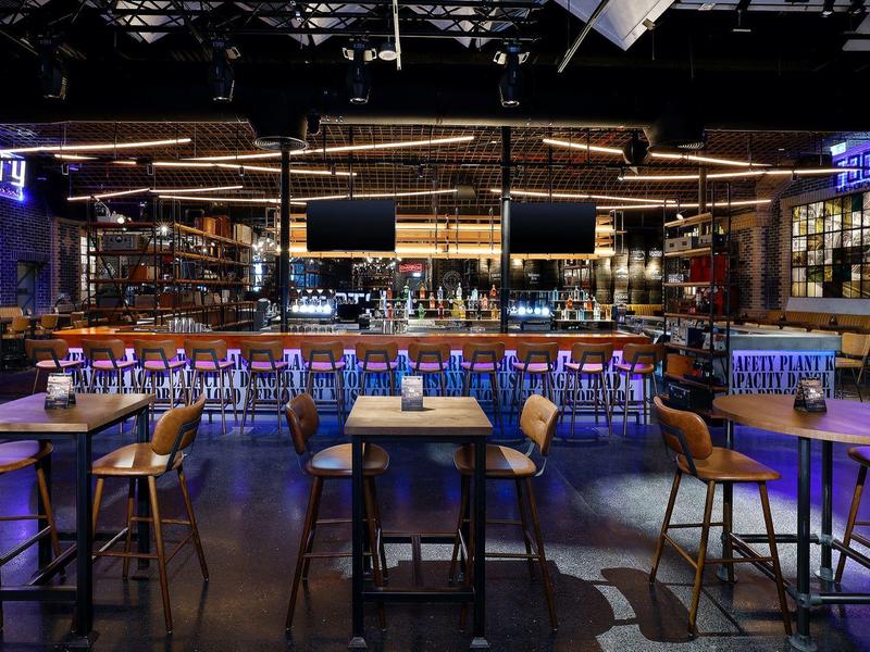 Moderne Bar mit hellblau beleuchtetem Tresen und Hockern in einem stilvollen Ambiente.