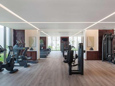 Moderner Fitnessbereich mit verschiedenen Trainingsgeräten und großen Fenstern