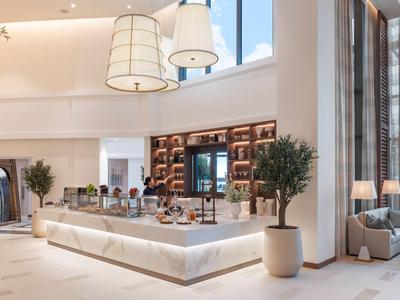 Moderner Hotelbarbereich mit Beleuchtung, Pflanzen und großen Fenstern.