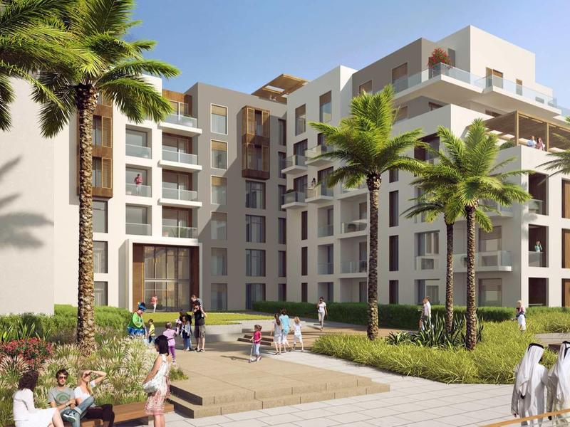 Moderner Wohnkomplex mit fünfstöckigen Gebäuden, großen Fenstern, Palmen und Gepflastertem Weg.