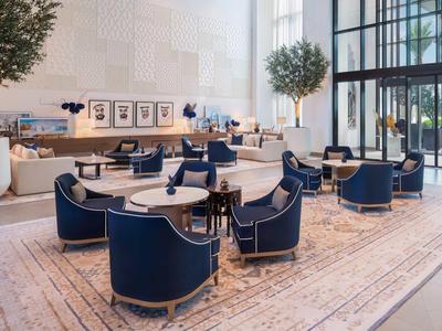 Moderner, heller Hotel-Loungebereich mit blauen Sesseln und großen Fenstern