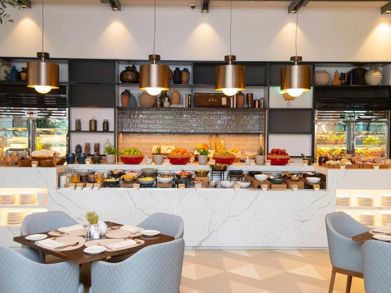 Modernes Buffet mit vielfältigen Speisen, gemütlichen Tischen und warmem Licht in elegantem Ambiente.