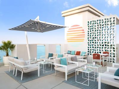 Moderne Terrasse mit stilvollen Sitzmöbeln und Sonnenschirm bei klarem Himmel.