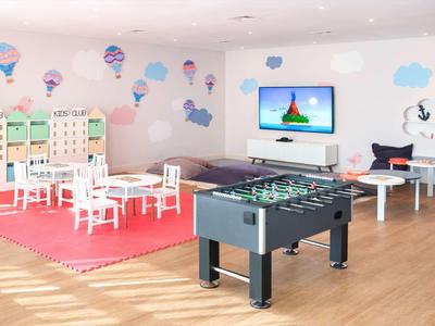 Kinderspielzimmer mit Tischfußball, kleinen Tischen, Stühlen und Wanddekorationen mit Heißluftballons.