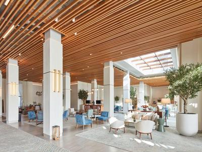 Heller, moderner Hotel-Lobby-Bereich mit Holzdecke, weißen Säulen und Sitzgruppen