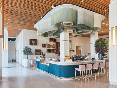 Modernes Café mit runder Bar, rosa Hockern und Holzdecke im Hotelinnenbereich