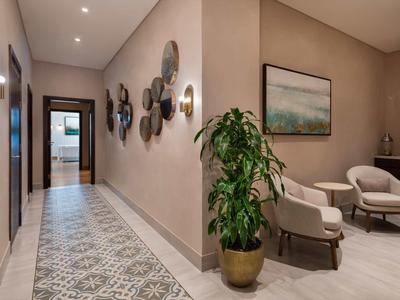 Moderner Flur mit gemustertem Boden, Wanddeko und Sitzbereich mit Pflanze und Stühlen.