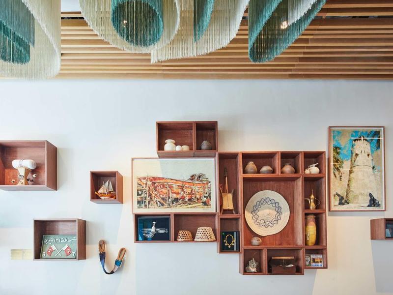 Weiße Wand mit Holzwürfeln, Bildern und dekorativen Gegenständen in harmonischer Anordnung.