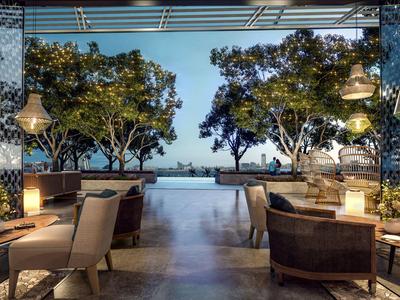 Espace extérieur élégant d'un hôtel avec sièges et vue sur la piscine et les arbres